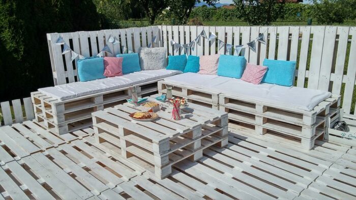 Wooden pallets as garden furniture with decorations on a sunny day in the garden.