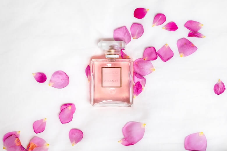 rosa parfymflaska med rosblad runtom