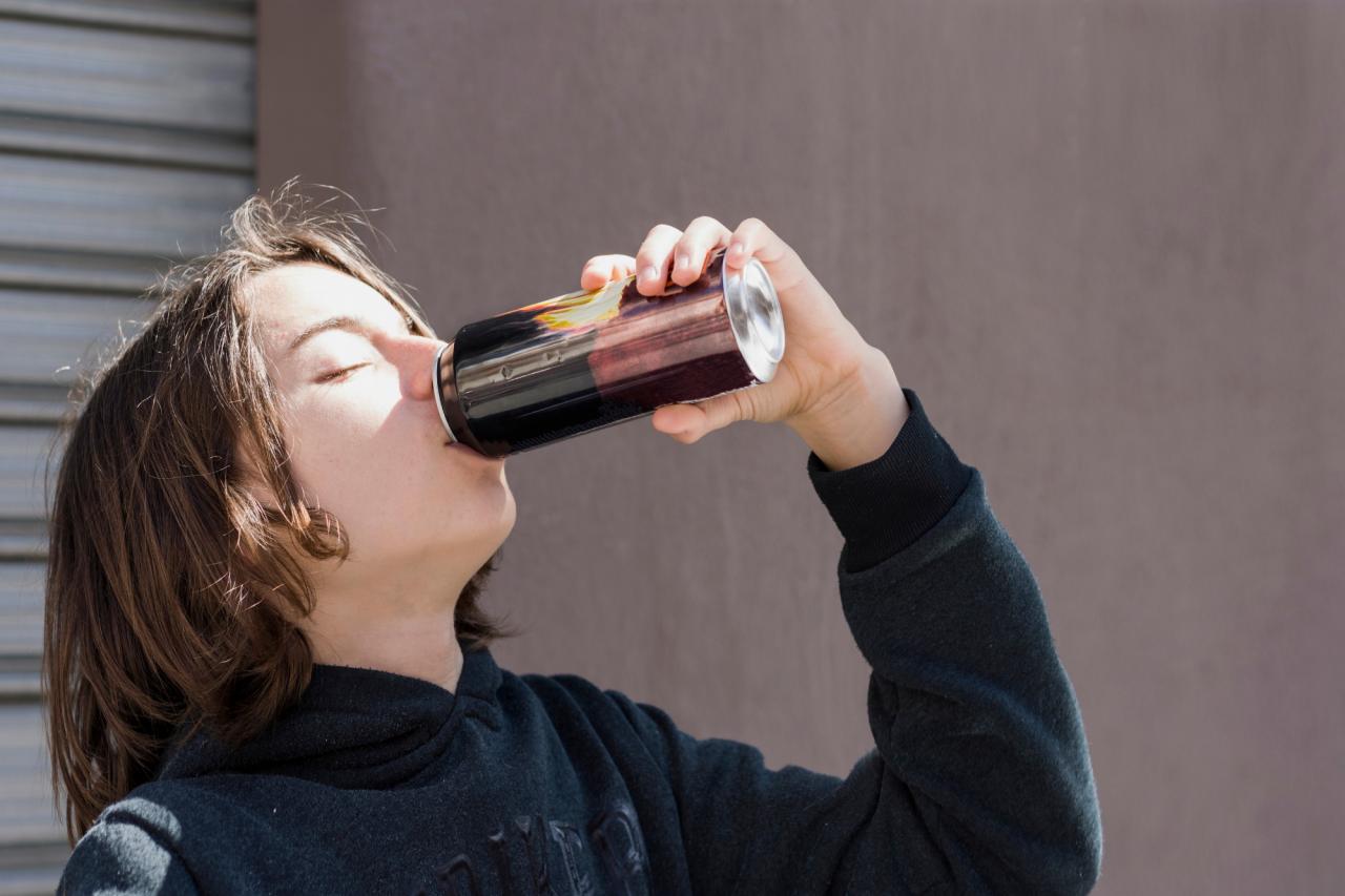 Chica de suéter negro tomándose una bebida energética