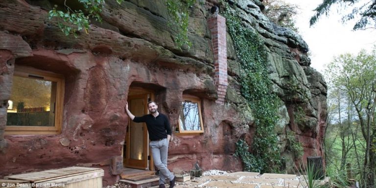 man standing near cave home