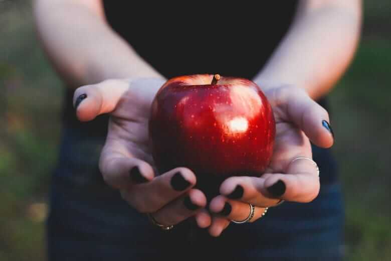 Jabłko trzymane w rękach przez kobietę