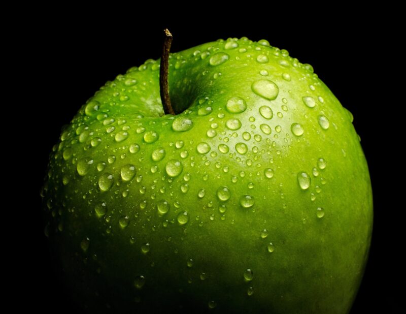 Zielone jabłko pokryte kroplami wody