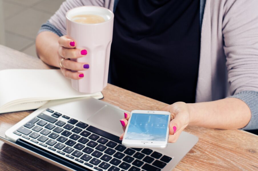 Kobieta przed laptopem ze smartfonem i sokiem jabłkowym w rękach