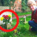 mujer frente a una tumba con flores rojas y amarillas