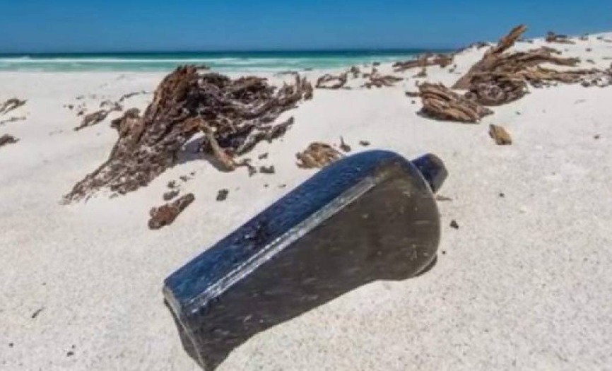 Botella de vidrío en la arena de la playa